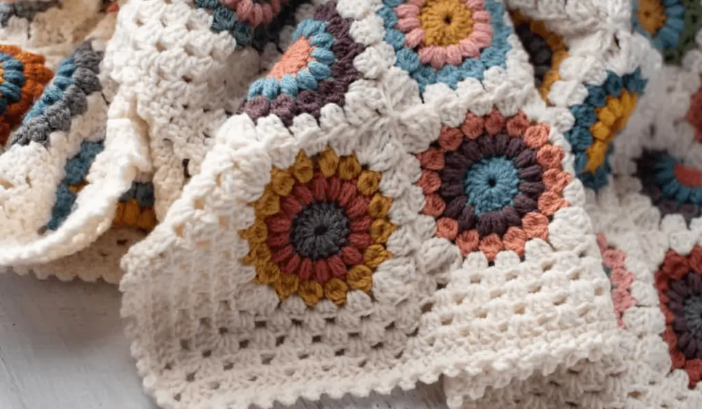 Flower afghan with multicolored flowers with a white yarn background.