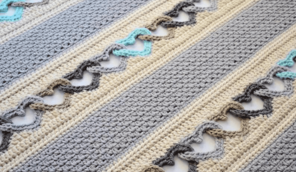 A crochet blanket with lines of crocheted hearts.