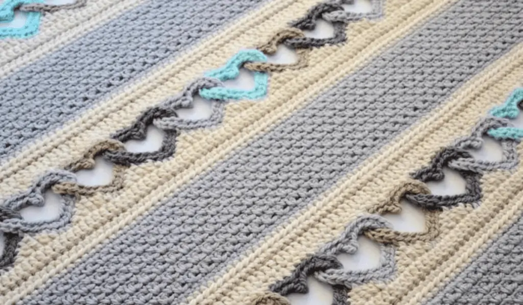 A crochet blanket with lines of crocheted hearts.