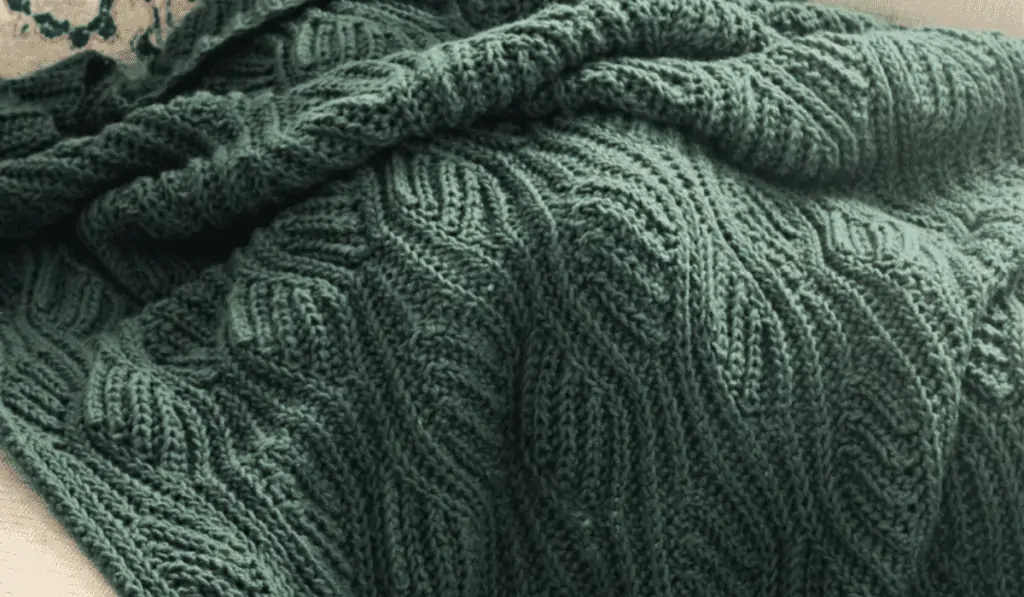 A green crocheted blanket with wavy looking rows.
