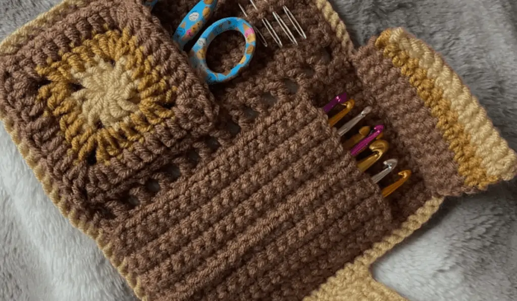 A brown crochet booklet that hold crochet hooks, sizzers, and a yarn needle.