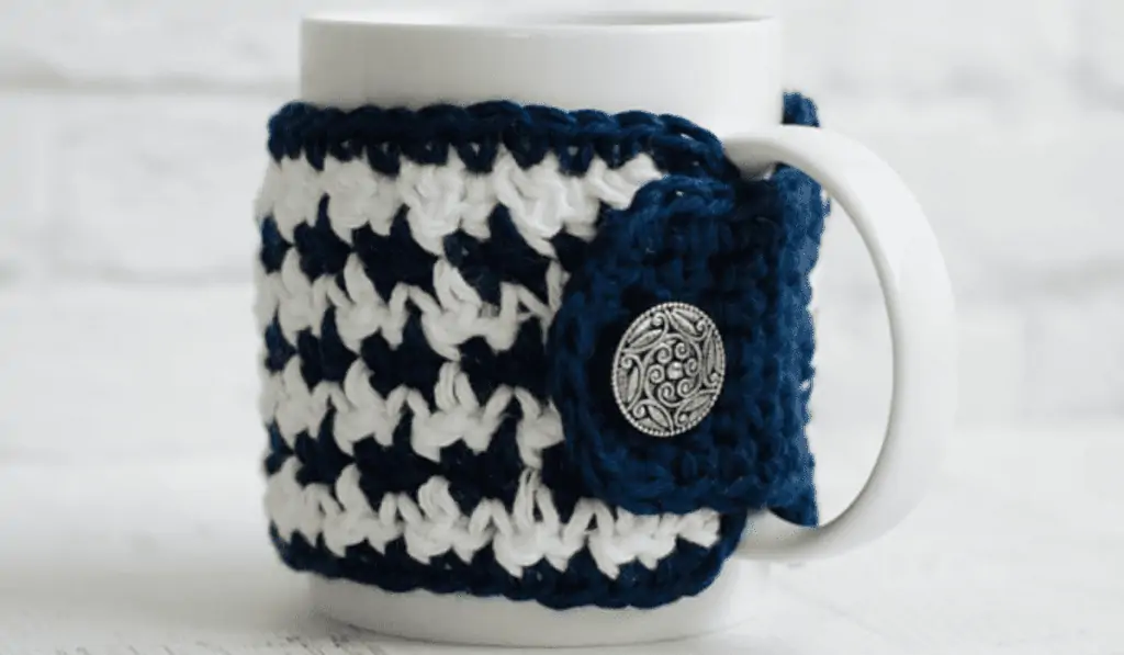 Blue and white crochet tea cozy with a metal button.