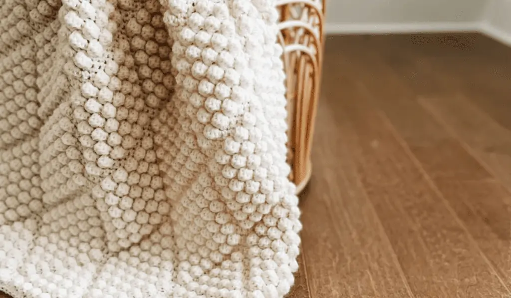 A white crochet blanket with diamond bobbles