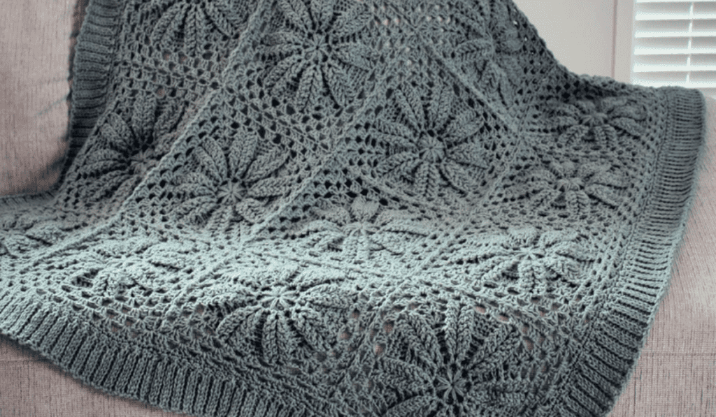 Grey flower square blanket laying over a sofa.
