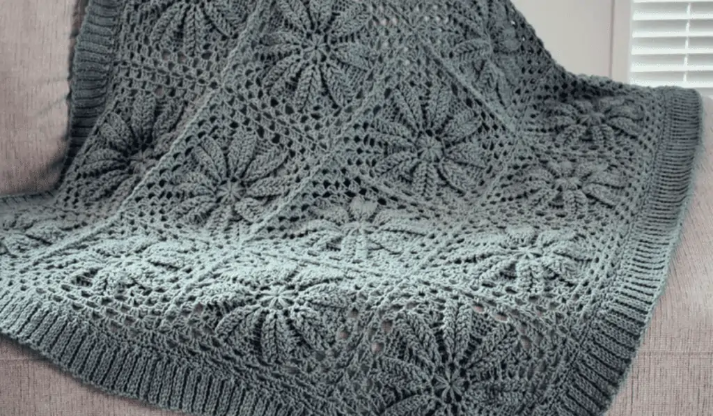 Grey flower square blanket laying over a sofa.