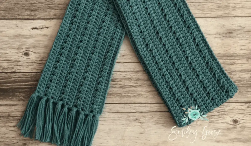 Green crochet scarf with tassels at the end.