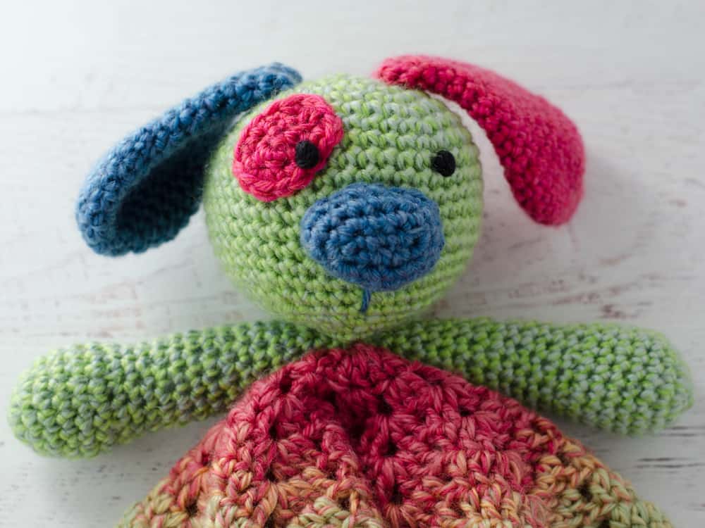 Up close features of crochet puppy lovey in green, blue and pink