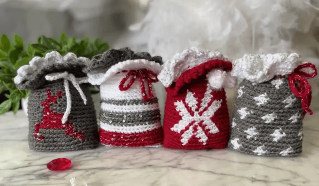 Christmas crochet gift bags, one with a reigndeer, one with stripes, one with a snowflake, one with spots.