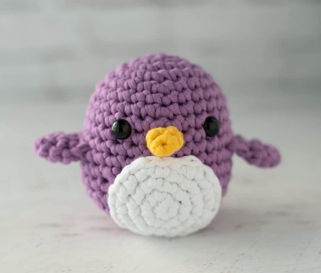 Purple crochet penguin with white circlet tummy and yellow beak