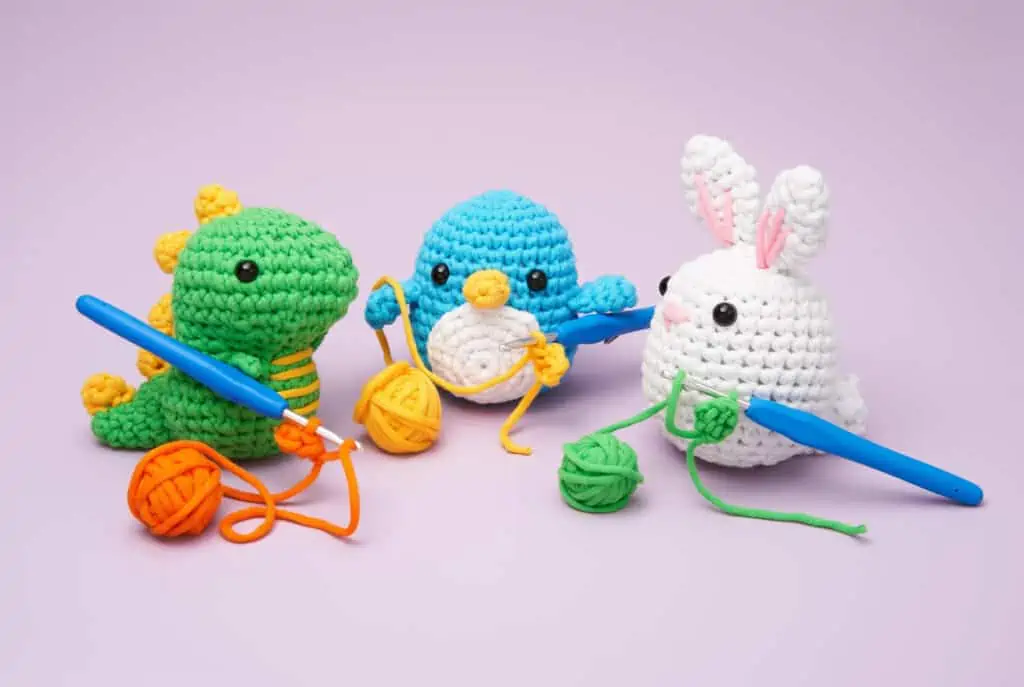 crochet dinosaur, crochet blue penguin and crochet bunny with yarn and crochet hooks