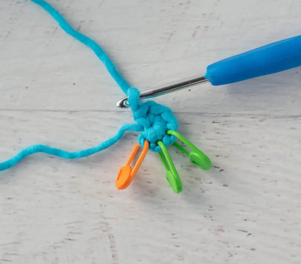 first round of crochet wooble with blue yarn, blue hook and multiple stitch markers