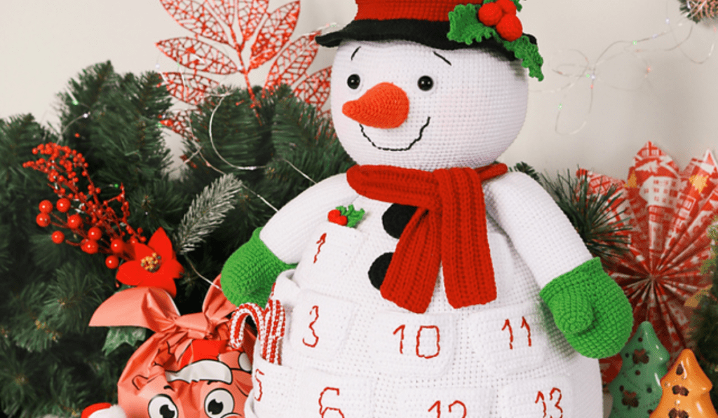 A snowman pillow with different crocheted pockets on it.