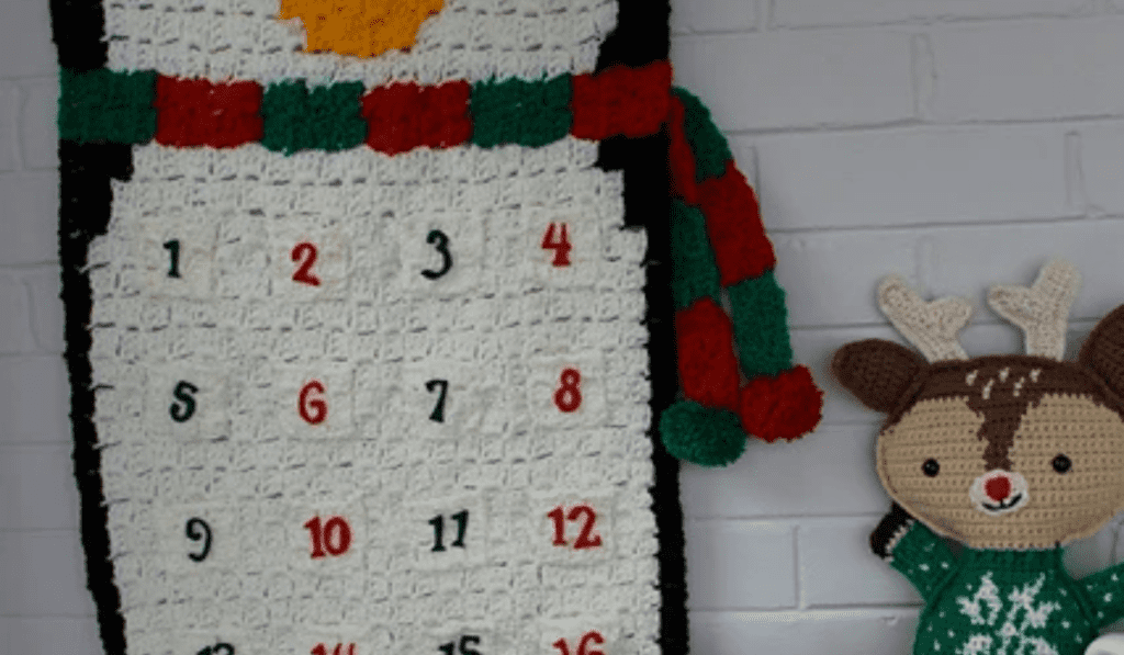 A penguin wall hanging with a scarf and numbered pockets.