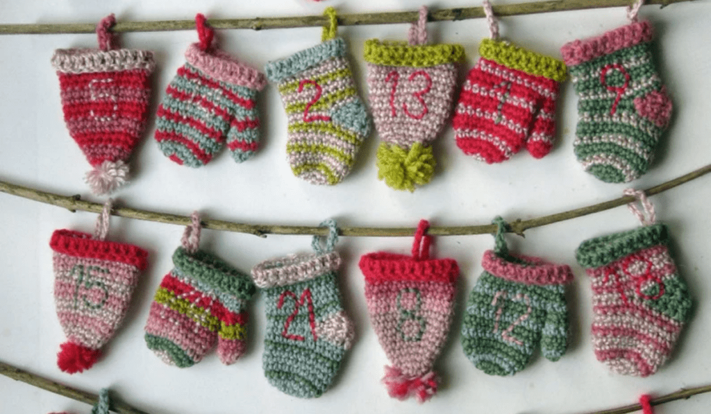 A row of bobble caps, mittons, and stockings handing on a branch. Each are dated and open to act as an advent calendar.