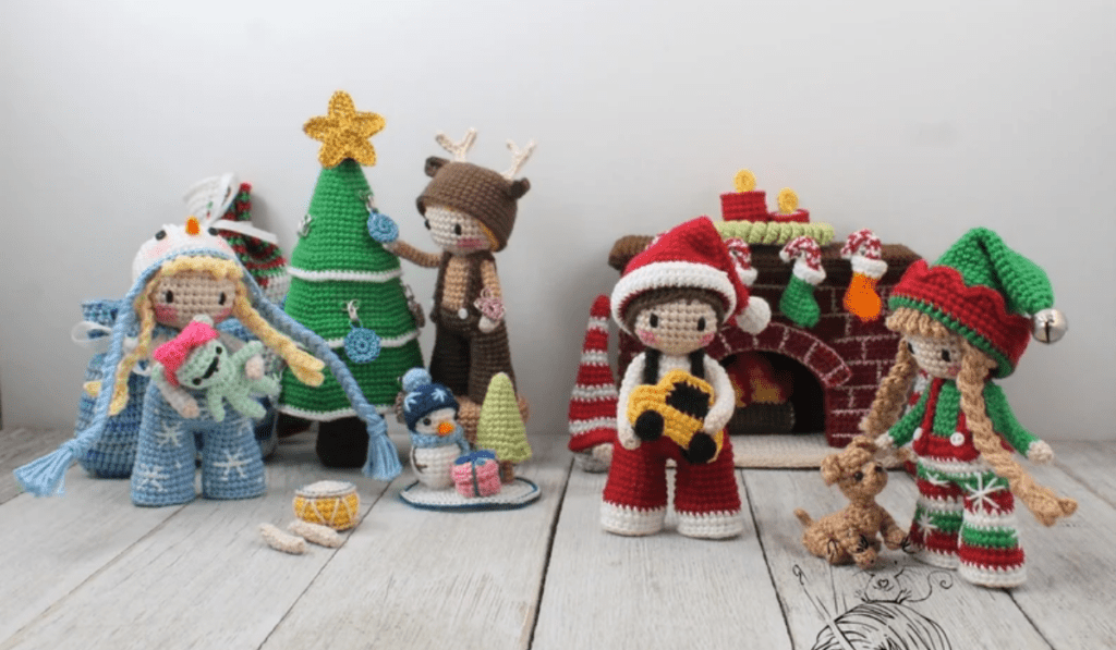A whole Christmas scene made of different amigurumis, there is a tree, multiple dolls, a fireplace, a uppy, little gifts, and so much more.