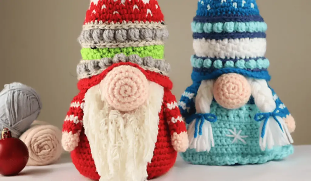 Two crochet gnomes, one that's red with a beard, one that's blue with pigtails.