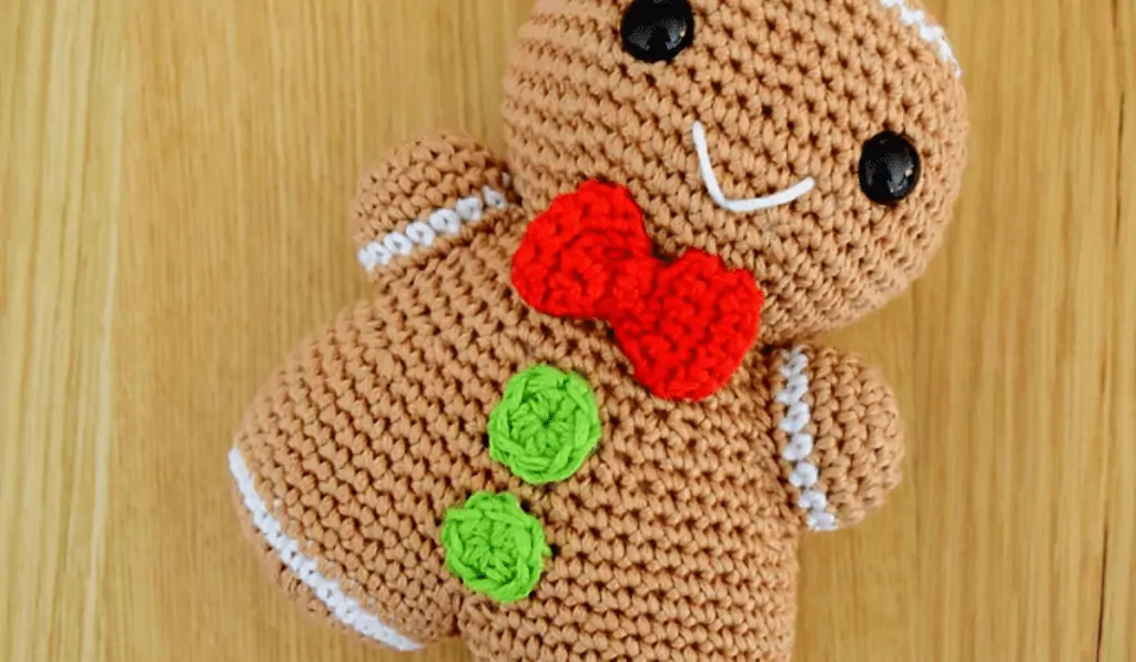 stuffed gingerbread man with a red bowtie and green buttons.