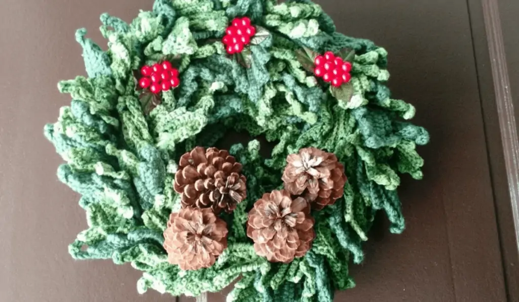 a classic Christmas wreath with individual leaves, holly berries, and four pine cones.