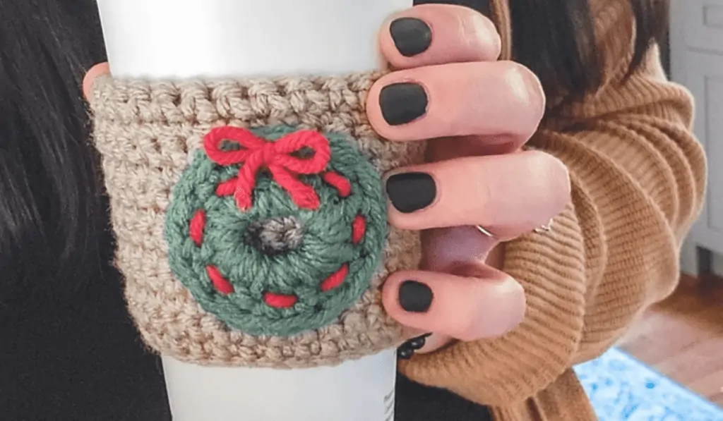 A mini wreath on a coffee cup cozy.