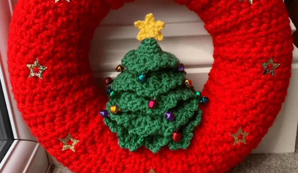 An all red crochet wreath with stare buttons and a Christmas tree in the center and little jingles bells for ornaments.