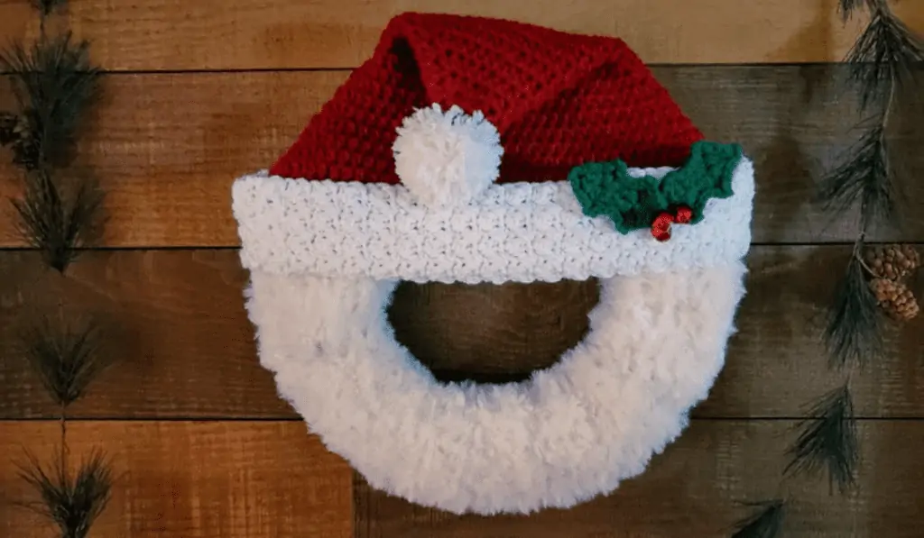 A wreath with a Santa hat and white yarn fake beard.