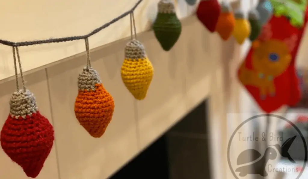 Crochet christmas lights on a garland in red, orange, yellow, and green.
