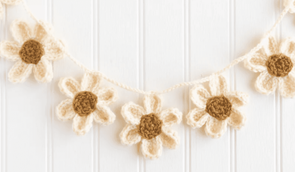 A daisy garland hanging with white planks behind it.