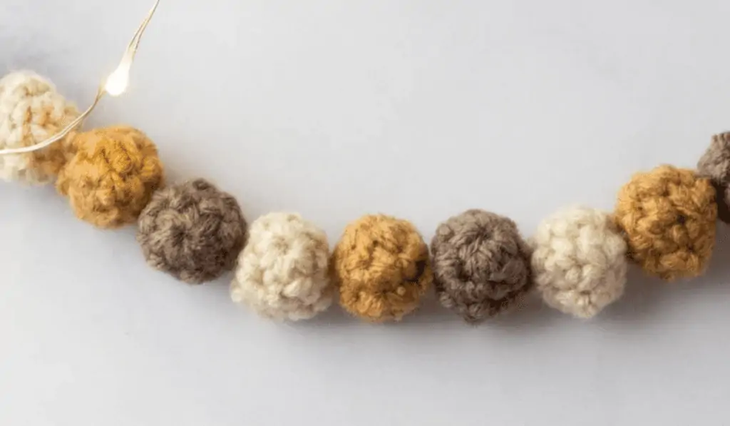 A garland of a crochet balls in white, yellow, and brown.