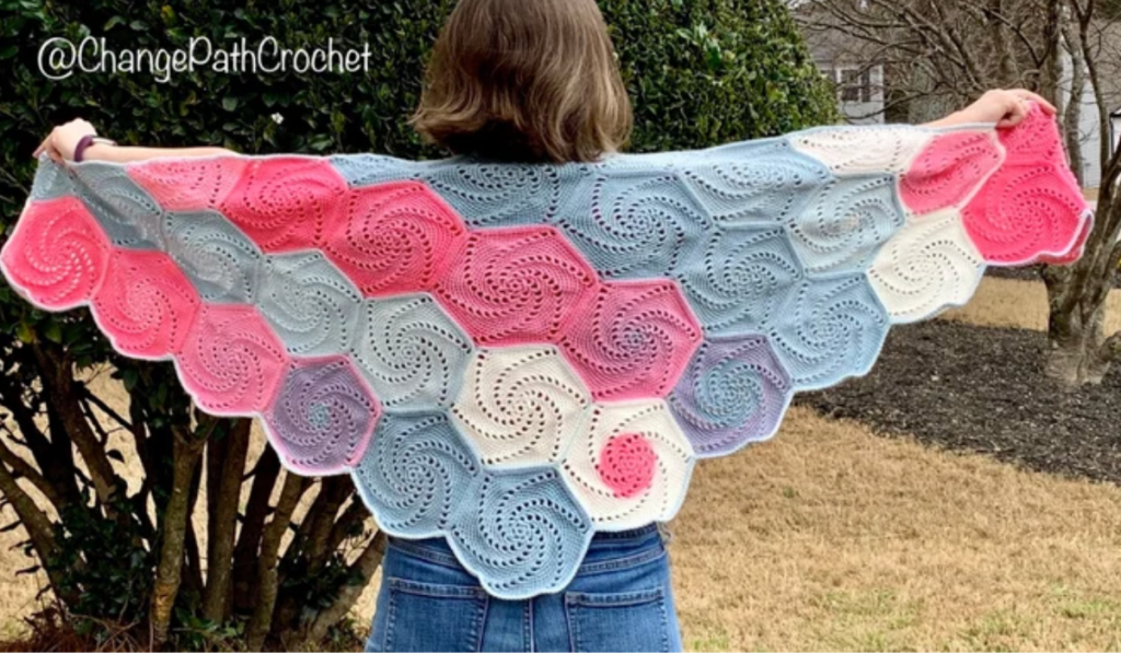 A crochet shawl made up of different swirly hexagons in a variety of colors.