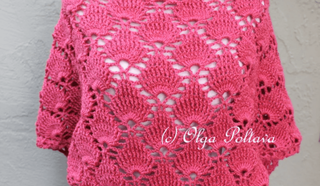 A pink crochet shawl that looks like it's made out of shells.
