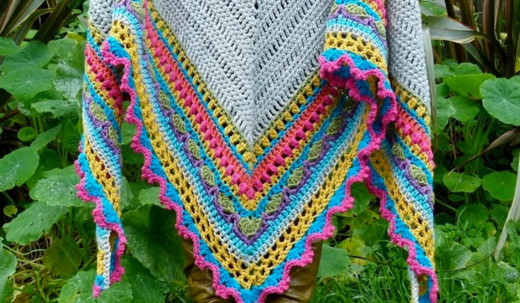 An all grey shawl with pink, blue, yellow, green, and purple strips of color along the end.
