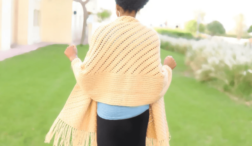 All white, rectangular crochet shawl draped over a women's shoulders.
