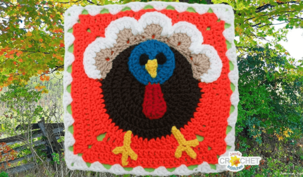 a granny square with a cartoon-style turkey with a blue face.