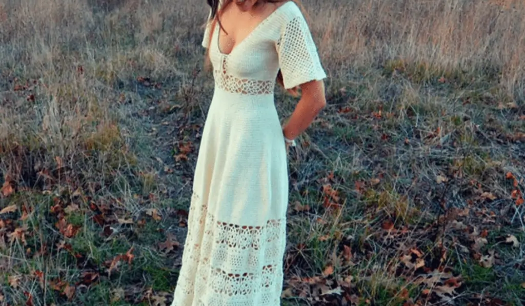 A long crochet wedding dress that features short sleeves and lace detailing that goes along the hem of the dress.