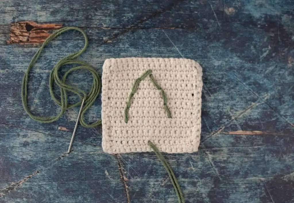 Back of white crochet coaster showing green stitches