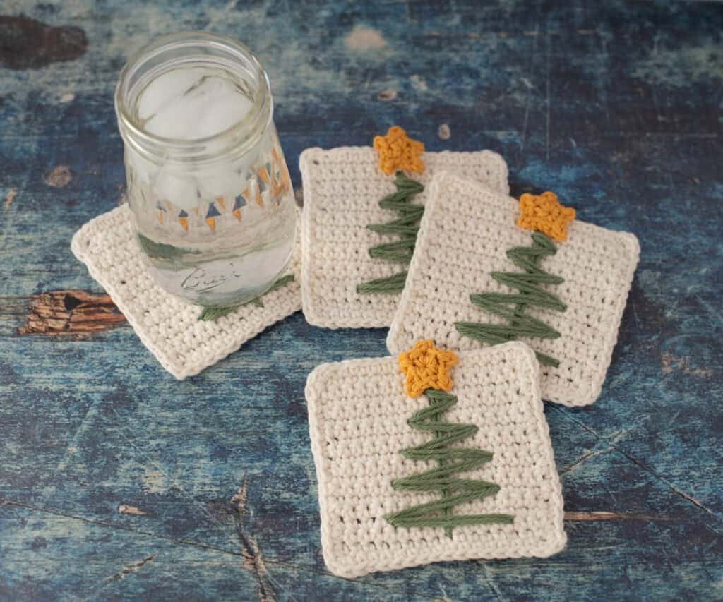 Crochet Christmas tree coasters with glass of ice water