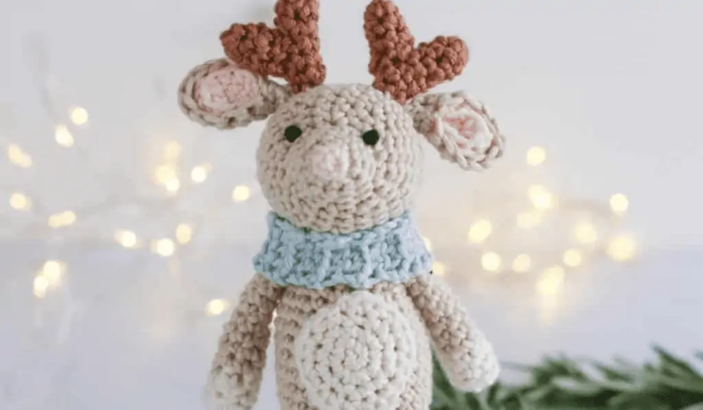 Amigurumi reindeer doll with a blue scarf.