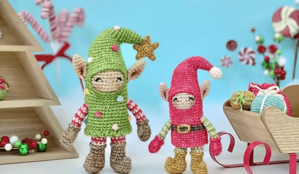 Amigurumi elves, one is taller and green with a star on top and one is pink and smaller with a little ball on top.