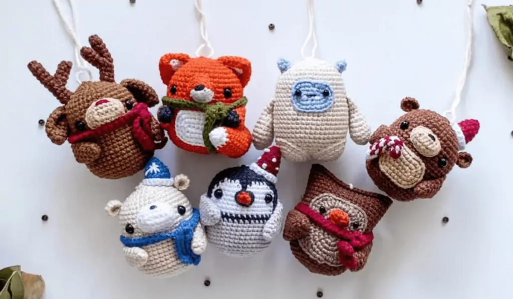 Seven amigurumi ornaments, a reindeer, a fox, a yeti, a bear, a polar bear, a penguin, and an owl.