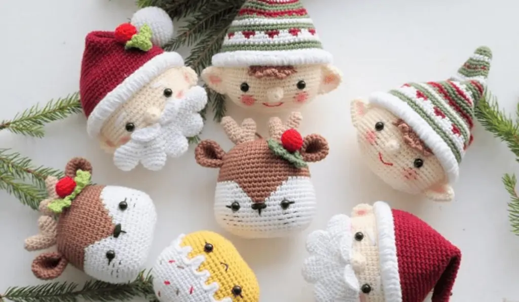 Seven amigurumi heads, two elves, two Santas, two reindeer, and on that looks like a cupcake with sprinkles.