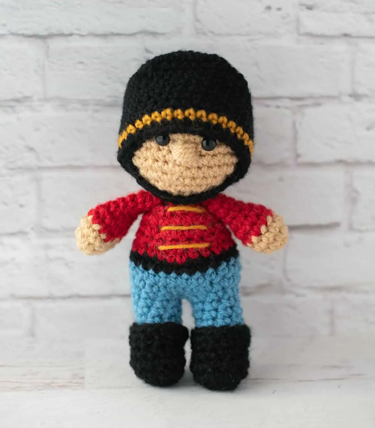 Crochet nutcracker doll, red shirt with gold trim, blue pants, black shoes and ha