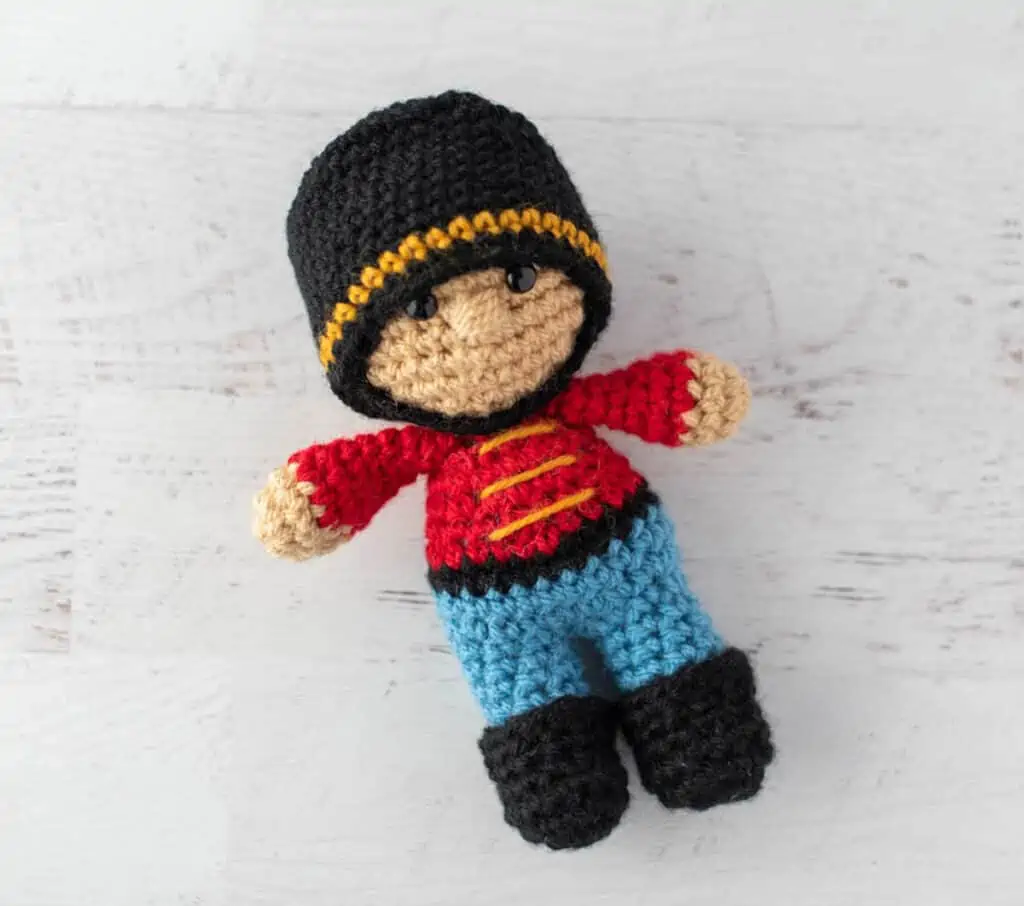 Crochet nutcracker doll, red shirt with gold trim, blue pants, black shoes and hat