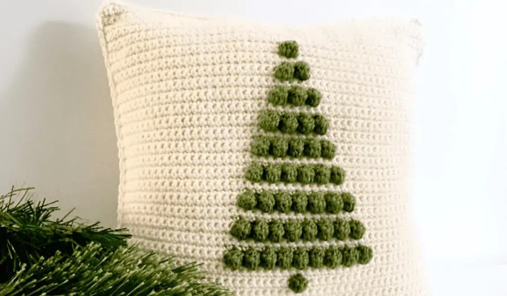 A white crochet pillow with a pine tree on it.