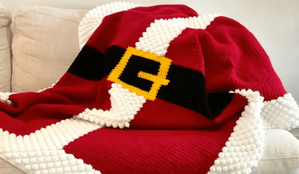 A crochet blanket that's all read with a gold buckle on it.