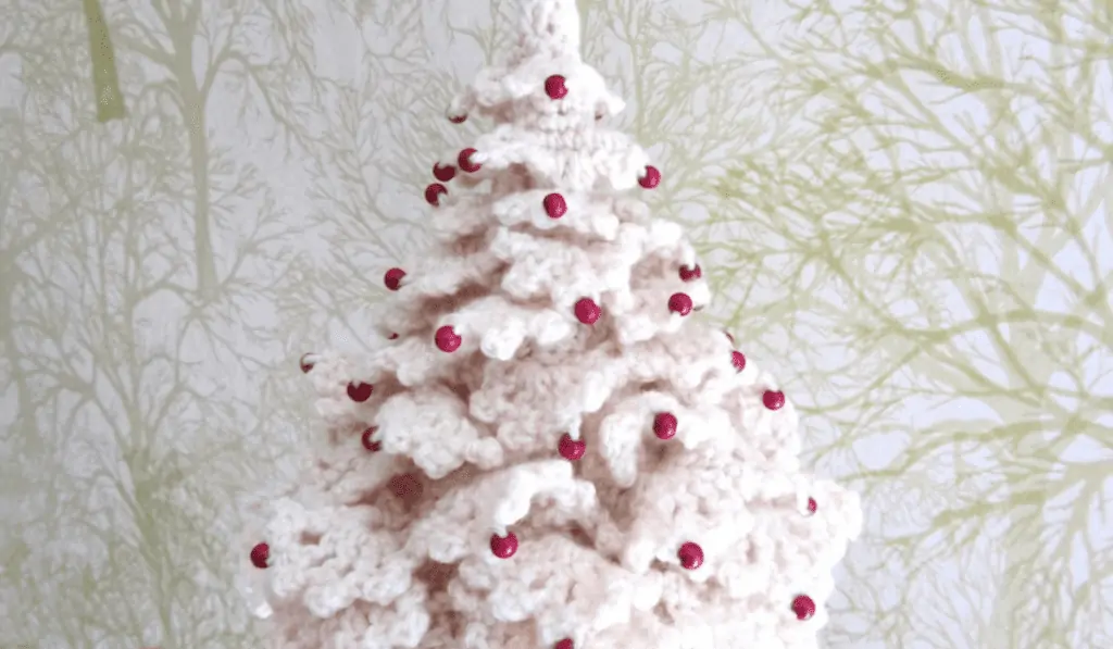 An all white crochet Christmas tree with red beads as ornaments.