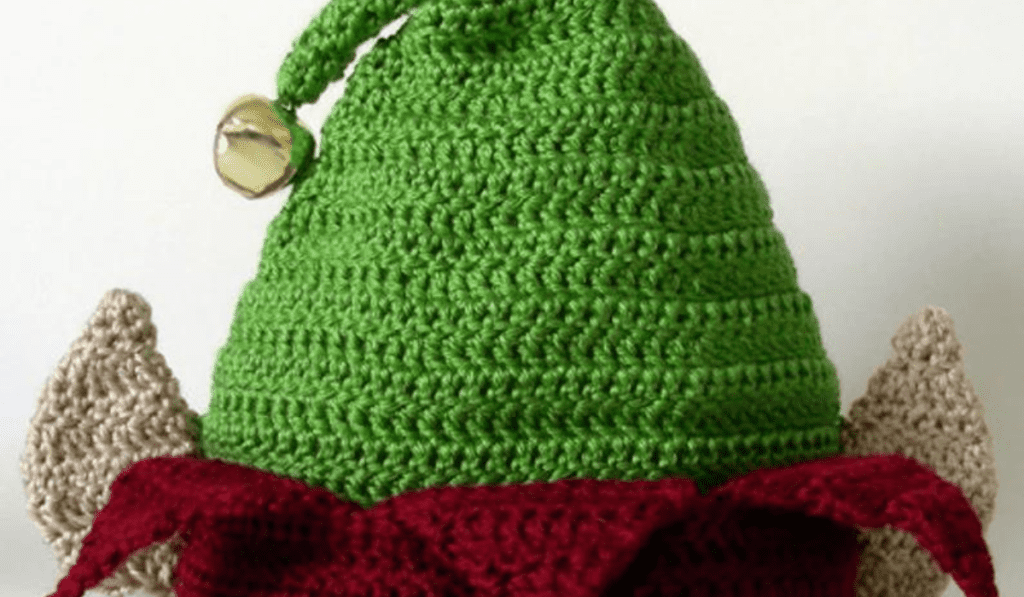 A green crochet elf hat with jingle bells on top and crochet elf ears.