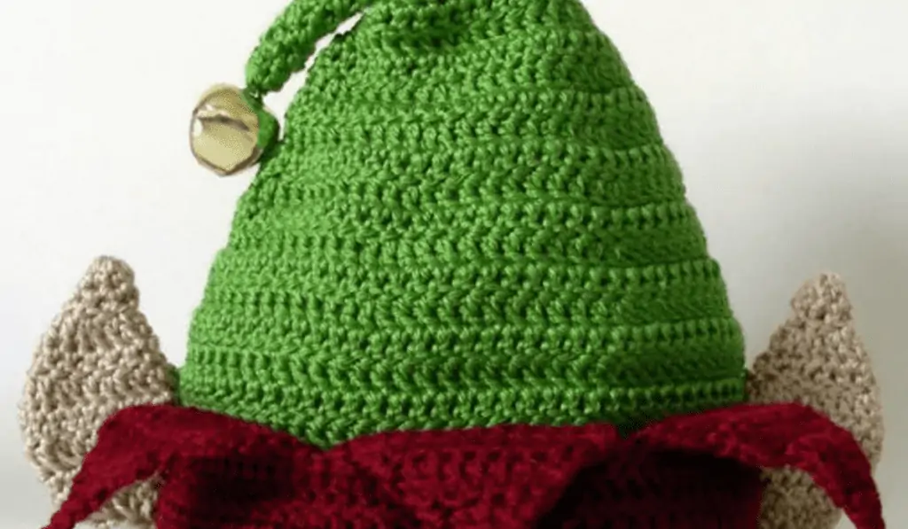 A green crochet elf hat with jingle bells on top and crochet elf ears.