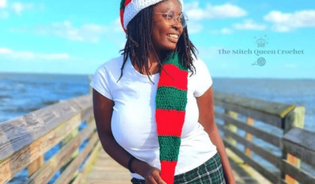 A long, dramatic crochet elf hat that is made out of red and green stipes of yarn.