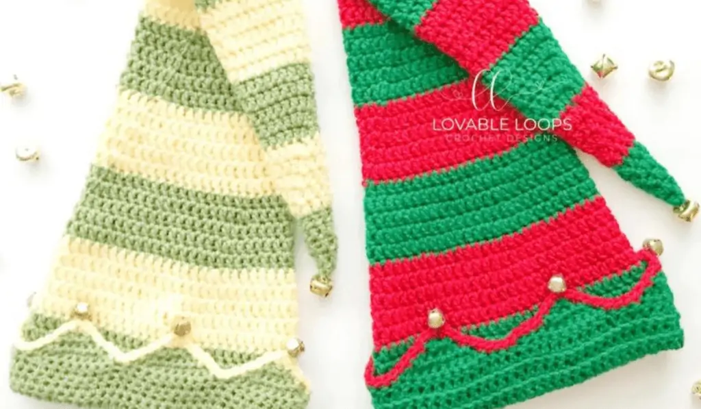 Large crochet elf hat with jingle bell detailing. One hat has green and red striping, and one has green and pale green stripes.