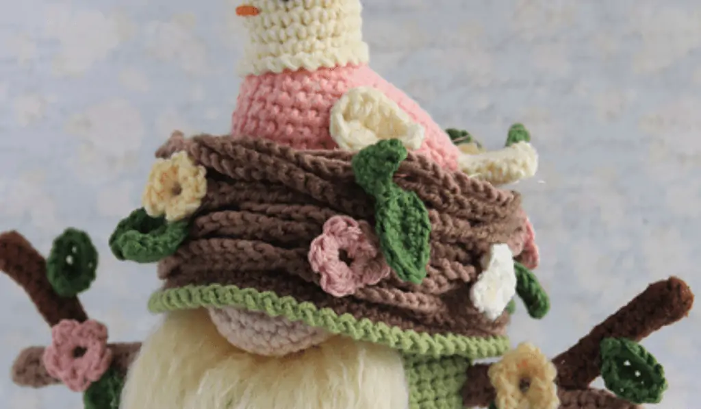 A garden gnome with a pink bird in a nest to act as a hat for the gnome.